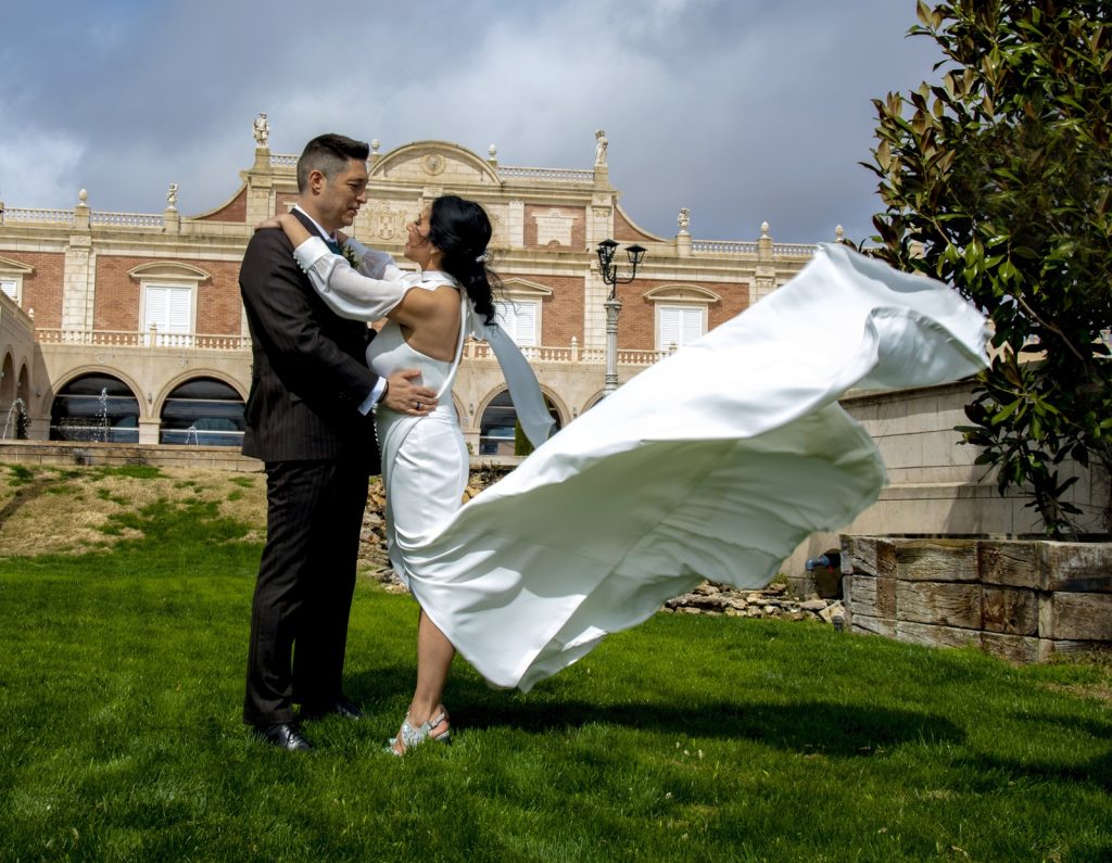 Novios abrazados durante una boda al aire libre con el vestido de la novia en movimiento
