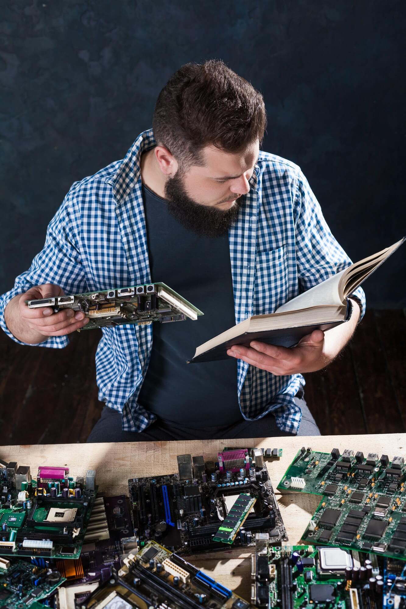 Soporte técnico mirando manual sobre placas electrónicas