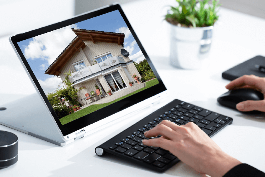 Persona utilizando un ordenador portatil con la foto de una casa