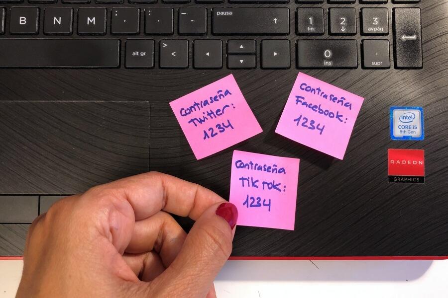 Persona anotando contraseñas de redes sociales en post it rosa
