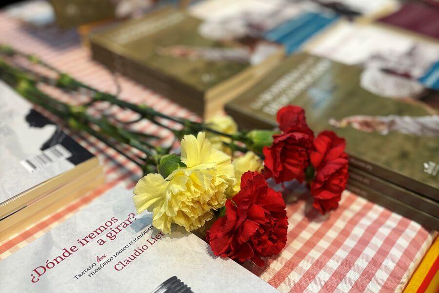 Claveles rojos y amarillos sobre libros de Zsa Zsa Zsú Ediciones en la Feria del Libro Aragonés de la Almozara